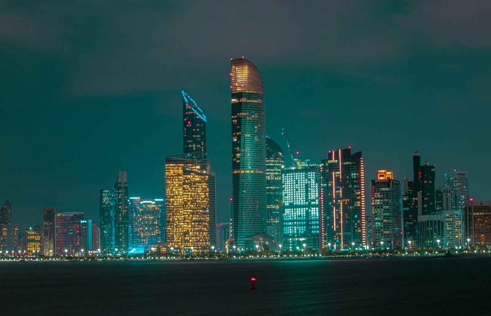 Abu Dhabi skyline illuminated at night, viewed across the water