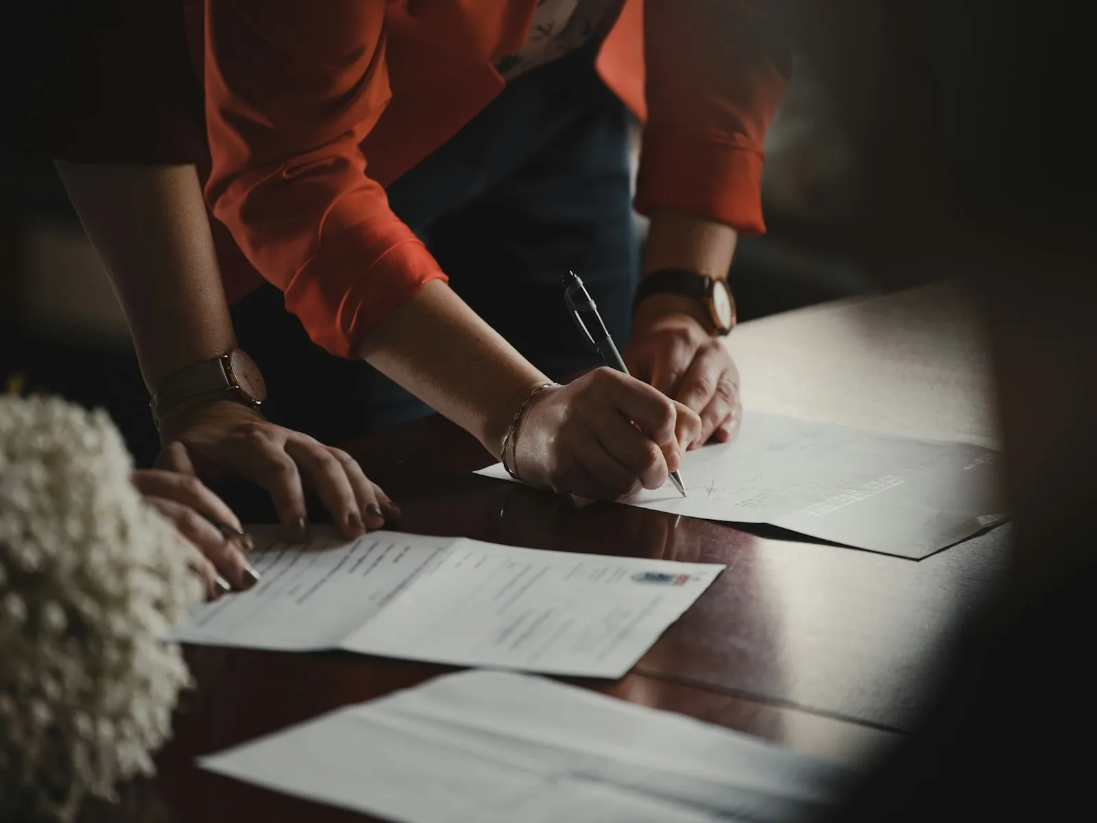 Two people signing legal documents at a desk